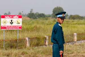 去年10月，边华空军基地，一名越南士兵站在二恶英污染危险警告标志旁。