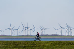 在德国的诺德尼，一个骑自行车的人在风力涡轮机前的堤岸上。